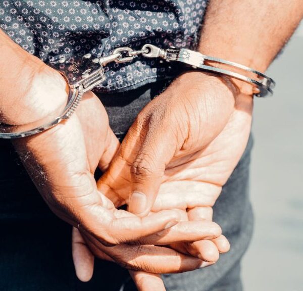 close up a hands handcuffed behind a man's back